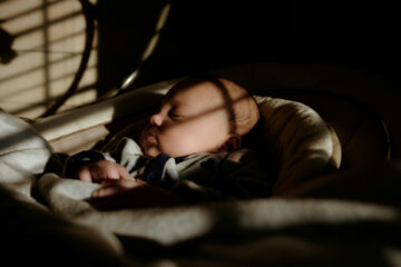 Baby in a crib showing the importance of blackout blinds for your baby's nursery